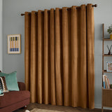 Caramel gold velvet eyelet curtains hanging on a dark wooden pole in a living room, shown with grey walls, framed wall art, and a wooden bookshelf.