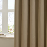 Mocha velvet eyelet curtain in soft folds beside a white-framed window, shown in a bedroom setting with a windowsill holding books.
