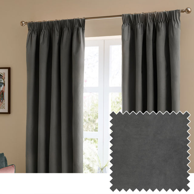 Charcoal grey velvet pencil pleat curtains with pinch-pleat heading hung on a chrome pole in a living room, shown beside a matt velvet fabric swatch.