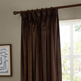 Chocolate brown velvet pencil pleat curtain with pencil pleat heading on a wooden pole, shown hanging beside a window in a living room setting.