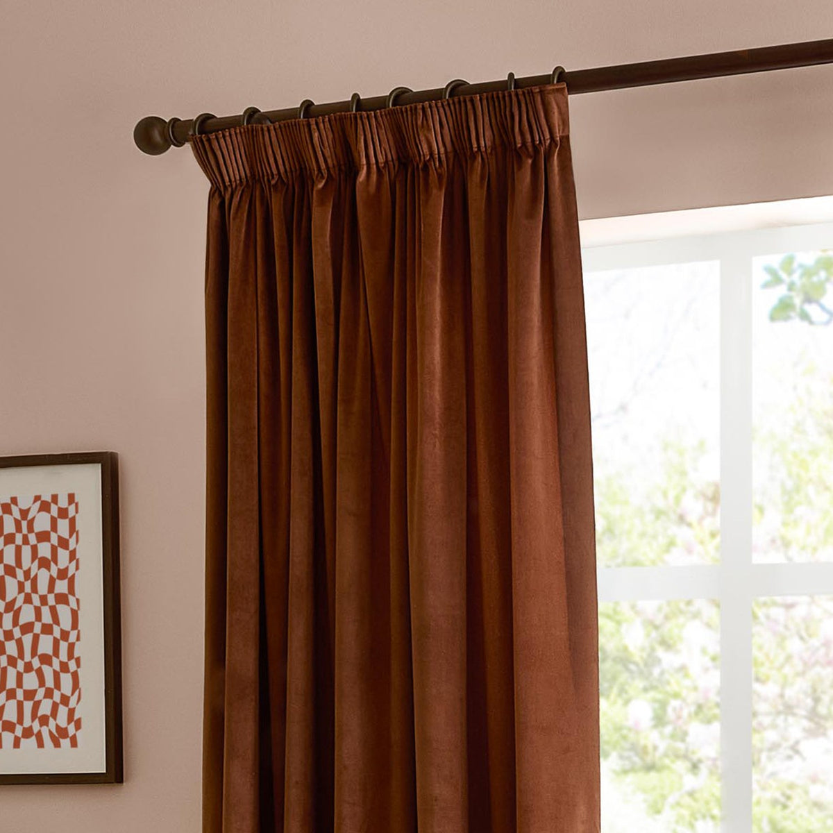 Mink velvet pencil pleat curtain with pinch-gathered heading and hook rings on a dark rod, hanging in soft folds beside a bright window.