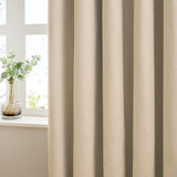 Natural pencil pleat velvet curtains in soft folds by a window, styled beside a glass vase with eucalyptus stems on a white sill.