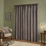 Silver-grey velvet pencil pleat curtains hung on a metal pole in a living room, shown as a full-length pair with a soft matt finish against sage green walls.