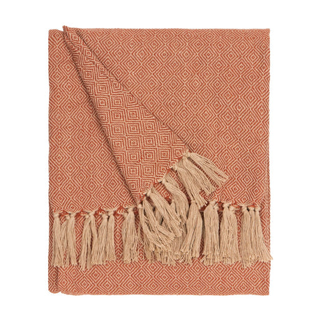 Dessa Geometric Polyester Throw in terracotta, folded to show a small diamond pattern in orange and cream with a knotted cream fringe edge, on a plain white background.