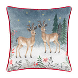 Square velvet cushion with printed reindeer and pine trees on a slate-blue snowy background, embroidered gold stars, floral border, and red piping, on a white background.