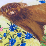 Close-up of the Daisy Hill Agnes velvet cotton cushion, showing embroidered blue cornflowers and a hand-painted Highland cow in brown tones on a yellow meadow ground.