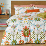 Cream cotton-blend Dilara Reversible Geometric Duvet Cover Set with folk-art bird and floral motifs in orange, olive, blue and pink, styled with matching pillowcases and accent cushions.