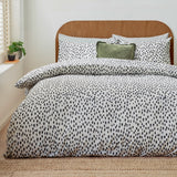 Dottie Printed Spotted Duvet Cover Set on a bed with matching pillowcases, black hand-painted spot pattern on white polycotton, styled with a green cushion in a bedroom setting.