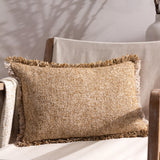 Doze Reversible Cotton Cushion in Biscuit, a rectangular scatter cushion with fringed edges in mixed biscuit and toffee tones, shown on a chair with neutral throws.