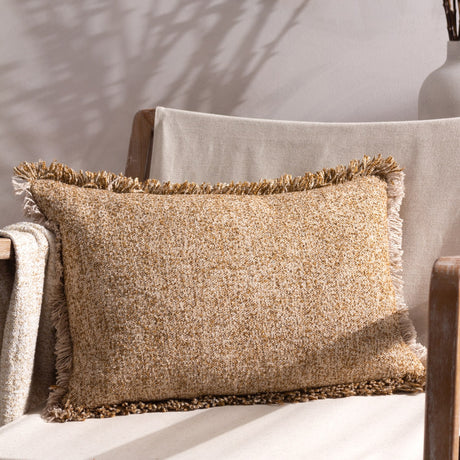 Doze Reversible Cotton Cushion in Biscuit, a rectangular scatter cushion with fringed edges in mixed biscuit and toffee tones, shown on a chair with neutral throws.