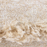 Close-up of the Doze Reversible Cotton Cushion in natural, showing the nubbly space-dyed weave in cream and sandy beige with a raw fringed trim edge.