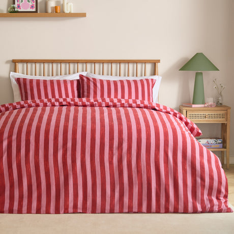 Dual Tone Printed Striped Duvet Cover Set in pink and red on a bed with matching pillowcases, styled with a wooden spindle headboard in a bedroom setting.