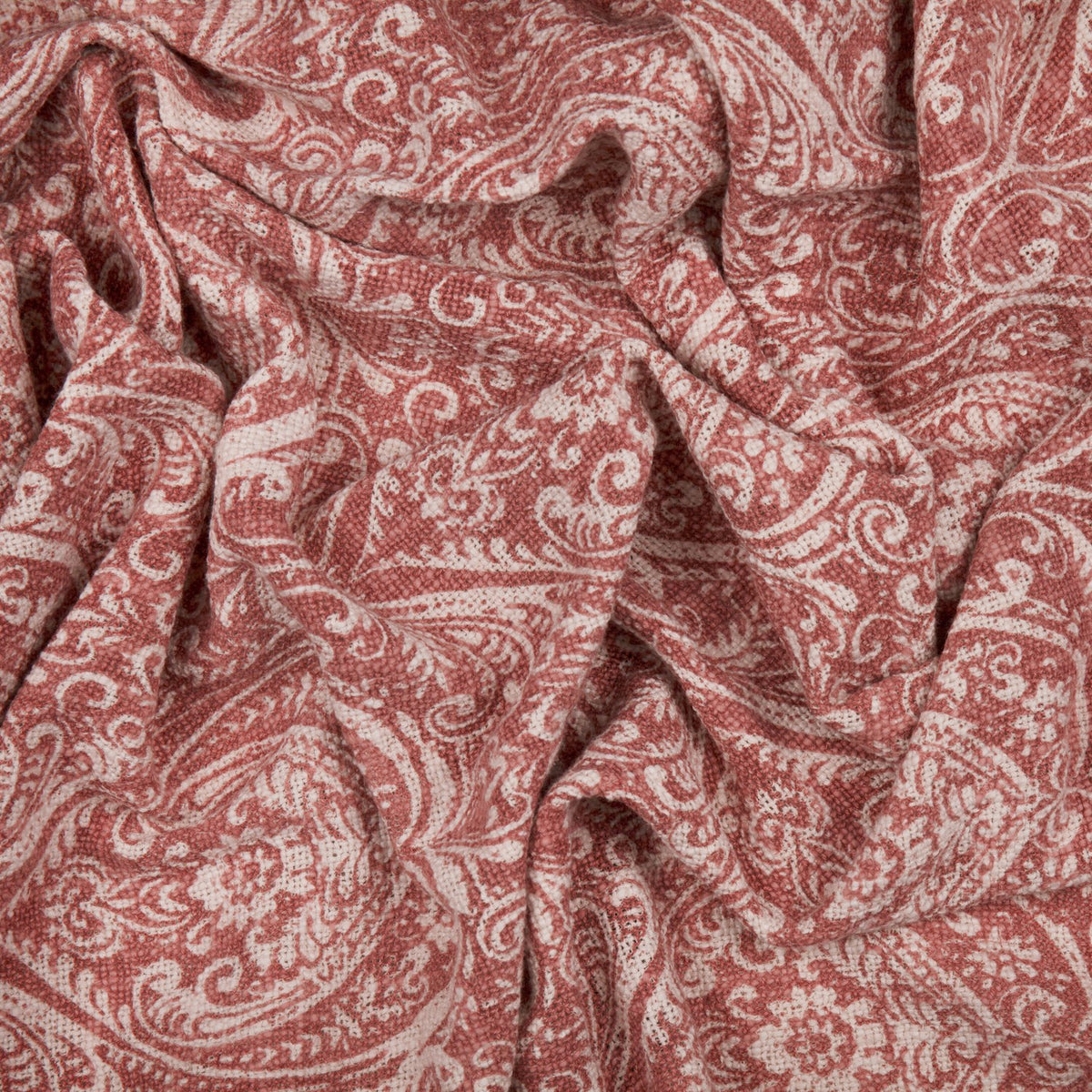 Durelle Damask Cotton Throw in coral, showing a draped paisley and floral pattern in coral pink on cream cotton fabric.