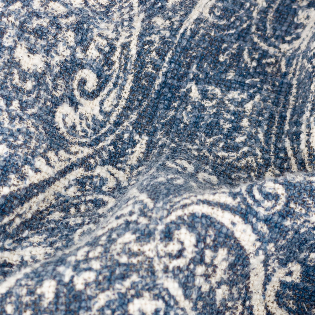 Close-up of the Durelle Damask Cotton Throw in Delph Blue, showing the woven cotton texture with an ivory-cream scrolling damask pattern across a deep blue ground.