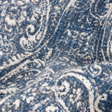 Close-up of the Durelle Damask Cotton Throw in Delph Blue, showing the woven cotton texture with an ivory-cream scrolling damask pattern across a deep blue ground.