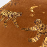 Close-up of the Dusk Animal Velvet Cushion in rust, showing embroidered monkeys, palm trees, and a crescent moon with stars stitched in gold and brown thread on velvet.