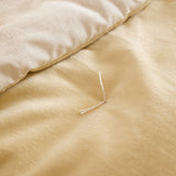 Close-up of the Edie quilted bedspread showing the butter yellow cotton velvet top folded back to reveal the paler natural linen-look reverse side.