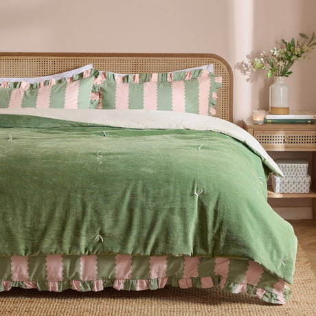 Edie Linen Cotton Bedspread in green on a bed with rattan headboard, quilted velvet face with hand-tied ties, paired with pink and green striped ruffled pillowcases in a bedroom setting.