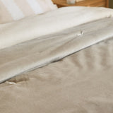 Edie Linen Cotton Bedspread in Natural, folded on a bed showing the soft velvet face and linen-look cotton reverse, styled with white and beige pillows.