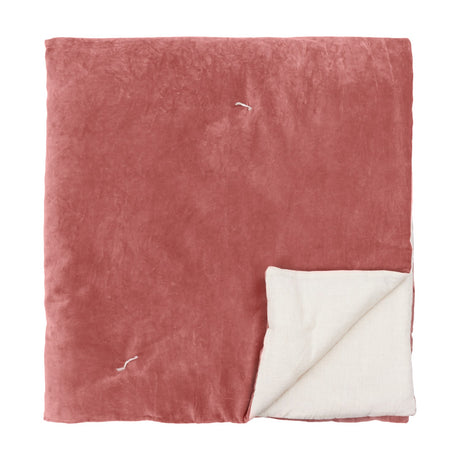 Edie Linen Cotton Bedspread in rose pink cotton velvet, quilted with tied stitches, folded to reveal a natural woven reverse, on a plain white background.