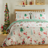 Elfie Printed Reversible Duvet Cover Set in cream and mint, dressed on a wooden bed with elf, Christmas tree, snowman and gift motifs, styled in a bedroom beside a decorated tree.