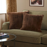 Two square Empress faux fur cushions in brown with dense textured pile, styled on an olive green sofa in a living room setting.