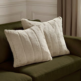 Two Empress square faux fur cushions in oatmeal with deep plush pile and vertical ribbed channels, styled on an olive green sofa.