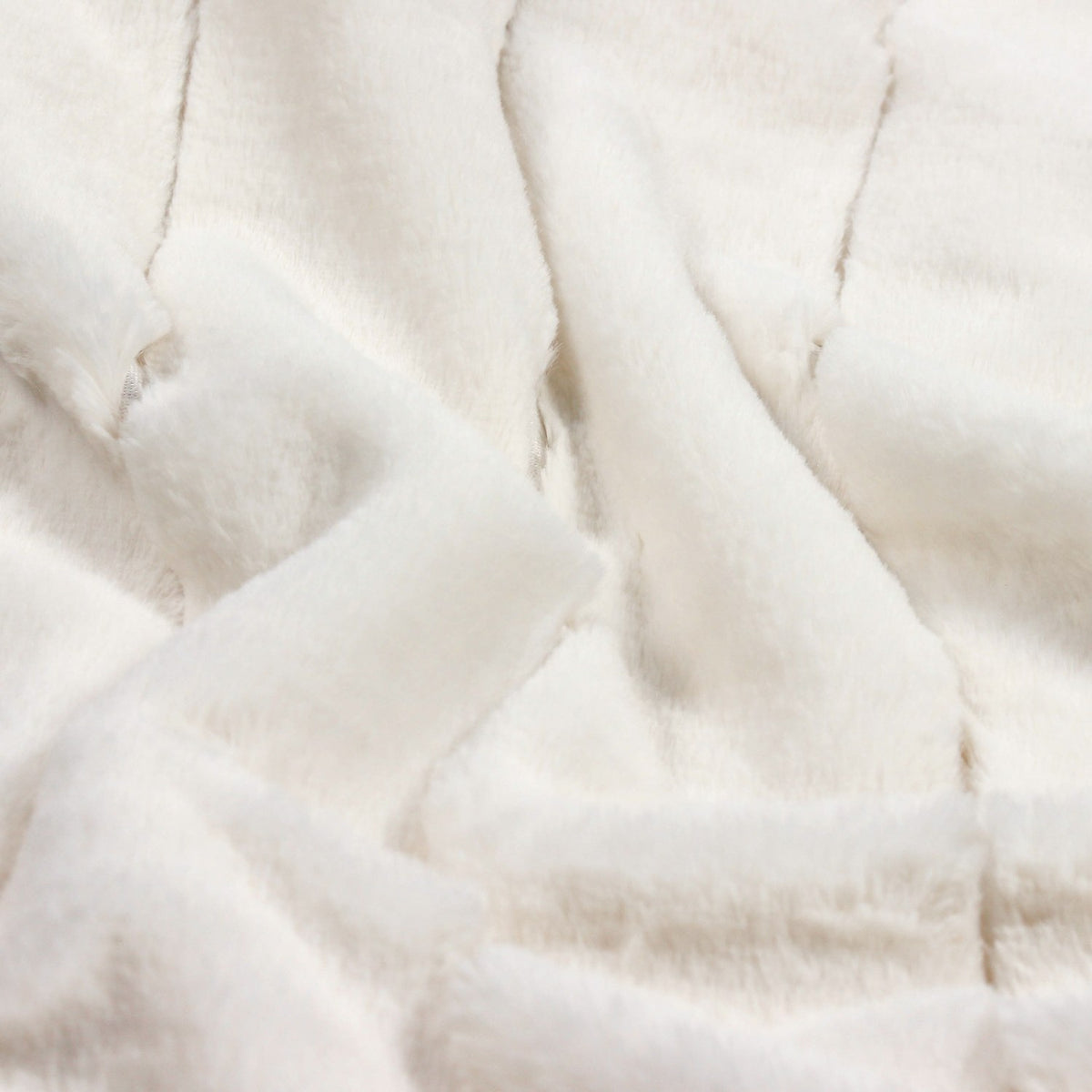 Close-up of the Empress Velvet Faux Fur Throw in cream, showing deep, long-piled fabric in soft ribbed vertical channels with a folded, textured surface.