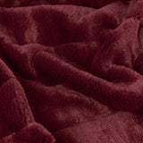 Close-up of the Empress Velvet Faux Fur Throw in ruby red, showing its plush, long-pile texture folded into soft draped layers.