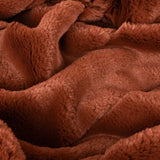 Close-up of the Empress Velvet Faux Fur Throw in rust, showing soft, long pile fabric folded into gentle waves in a rich reddish-brown tone.