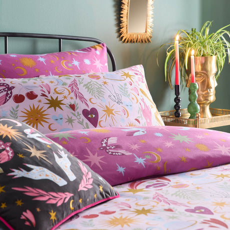 Pink Enchanted Printed Reversible Duvet Cover Set with celestial gold star, moon and heart motifs, matching pillowcases, solid magenta reverse, and patterned cushions on a bed.
