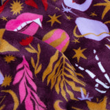 Enchanted Printed Polyester Throw in pink, close-up of plum fleece fabric with lips, stars, feathers and mystical print in pink, gold, lilac and cream.