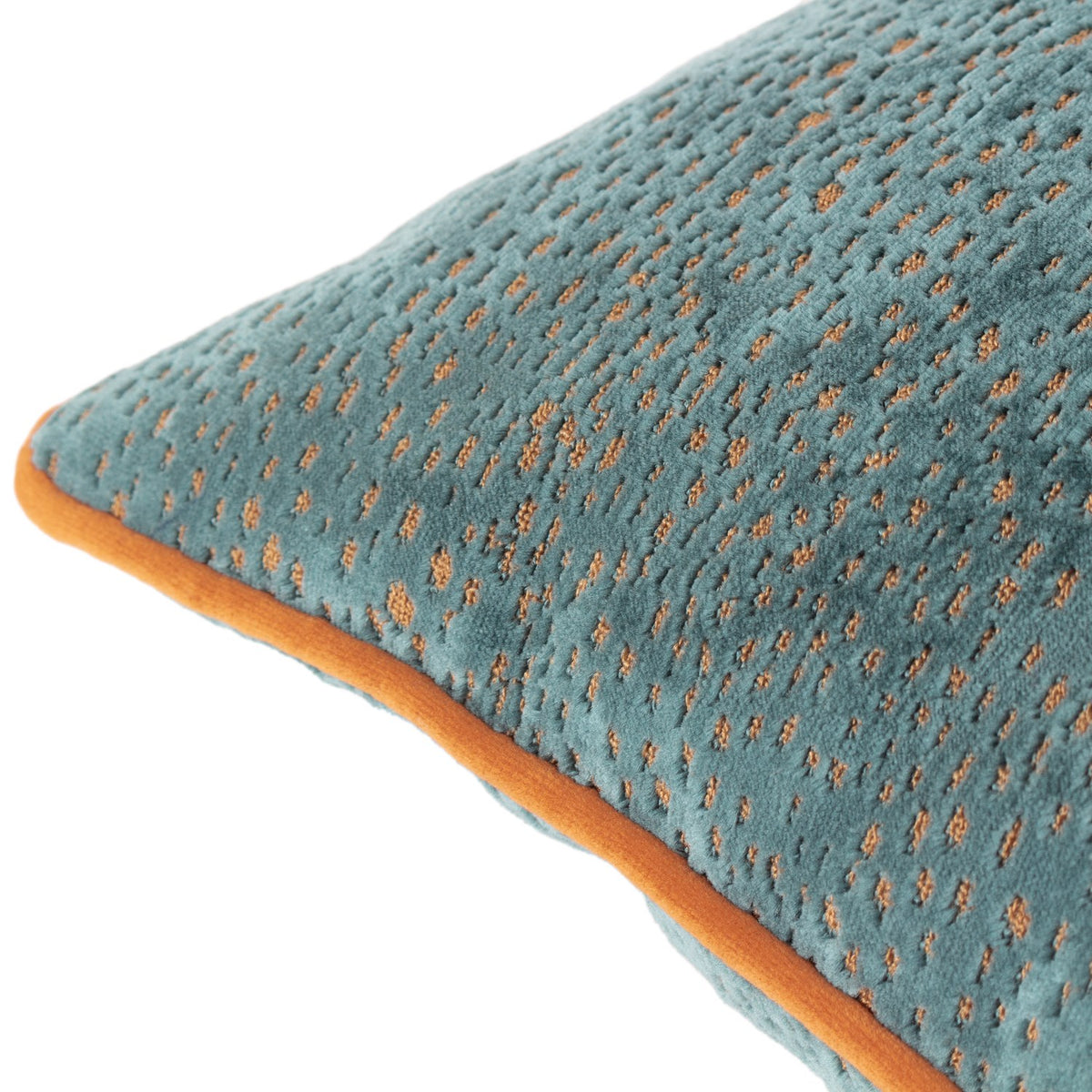 Close-up of the Estelle Reversible Velvet Cushion in teal with amber-rust spotted texture and contrast orange piping, shown on a white background.