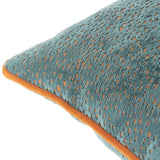 Close-up of the Estelle Reversible Velvet Cushion in teal with amber-rust spotted texture and contrast orange piping, shown on a white background.