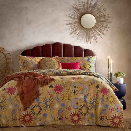 Ethereal Reversible Abstract Duvet Cover Set in Gold Rust, styled on a bed with sun and moon celestial print in pink, rust and cobalt blue, shown with a rust throw and matching pillow.