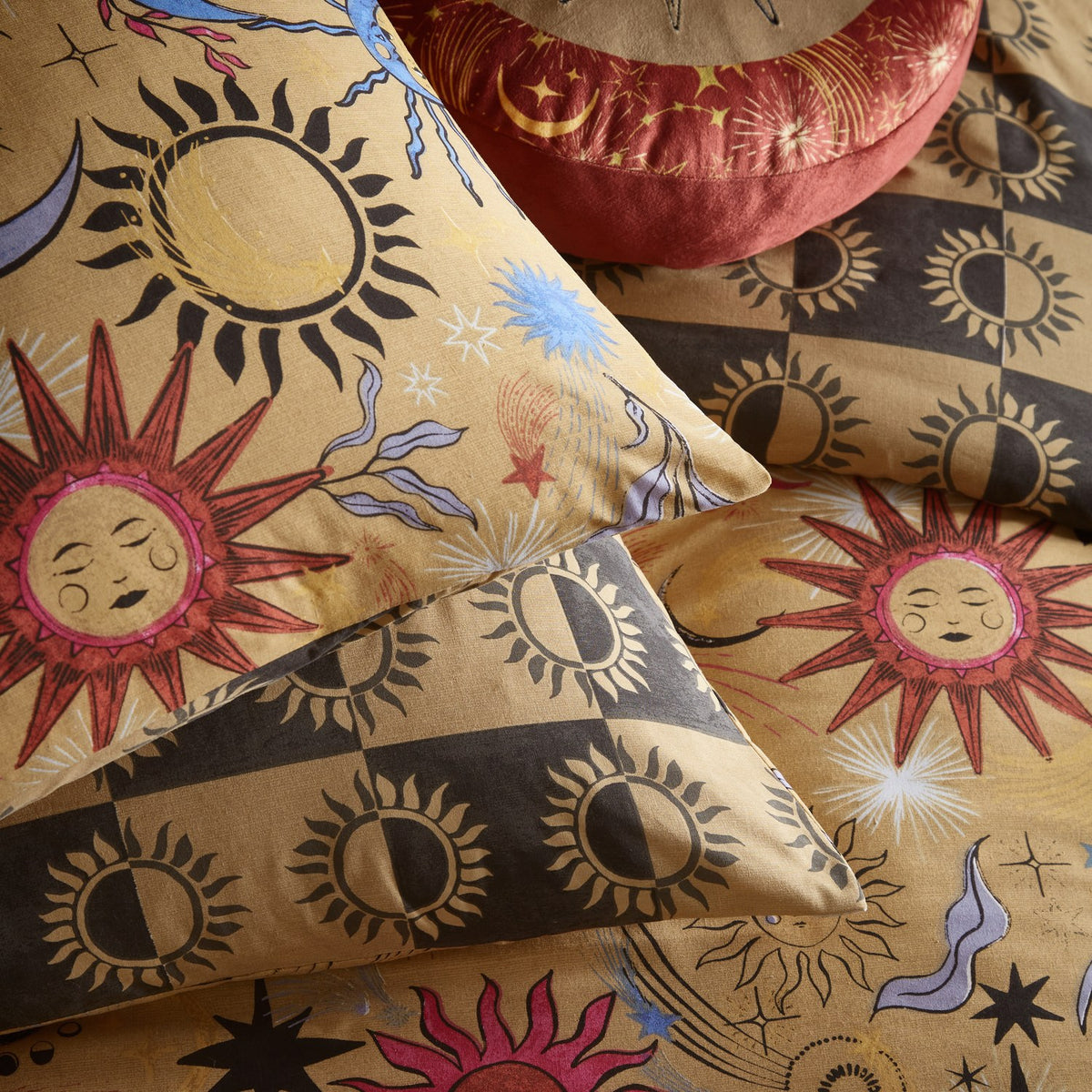 Ethereal Reversible Abstract Duvet Cover Set in Gold Rust, shown with matching pillowcases featuring sun-face and moon prints, reverse side in gold and grey checkerboard sun pattern.