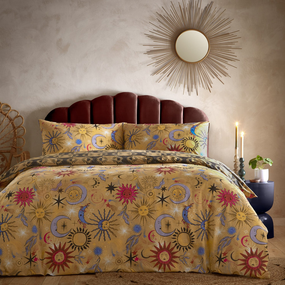 Reversible Ethereal Abstract Duvet Cover Set in Gold Rust with celestial sun and moon prints in pink, rust and cobalt blue, styled on a bed with velvet headboard and sunburst mirror.
