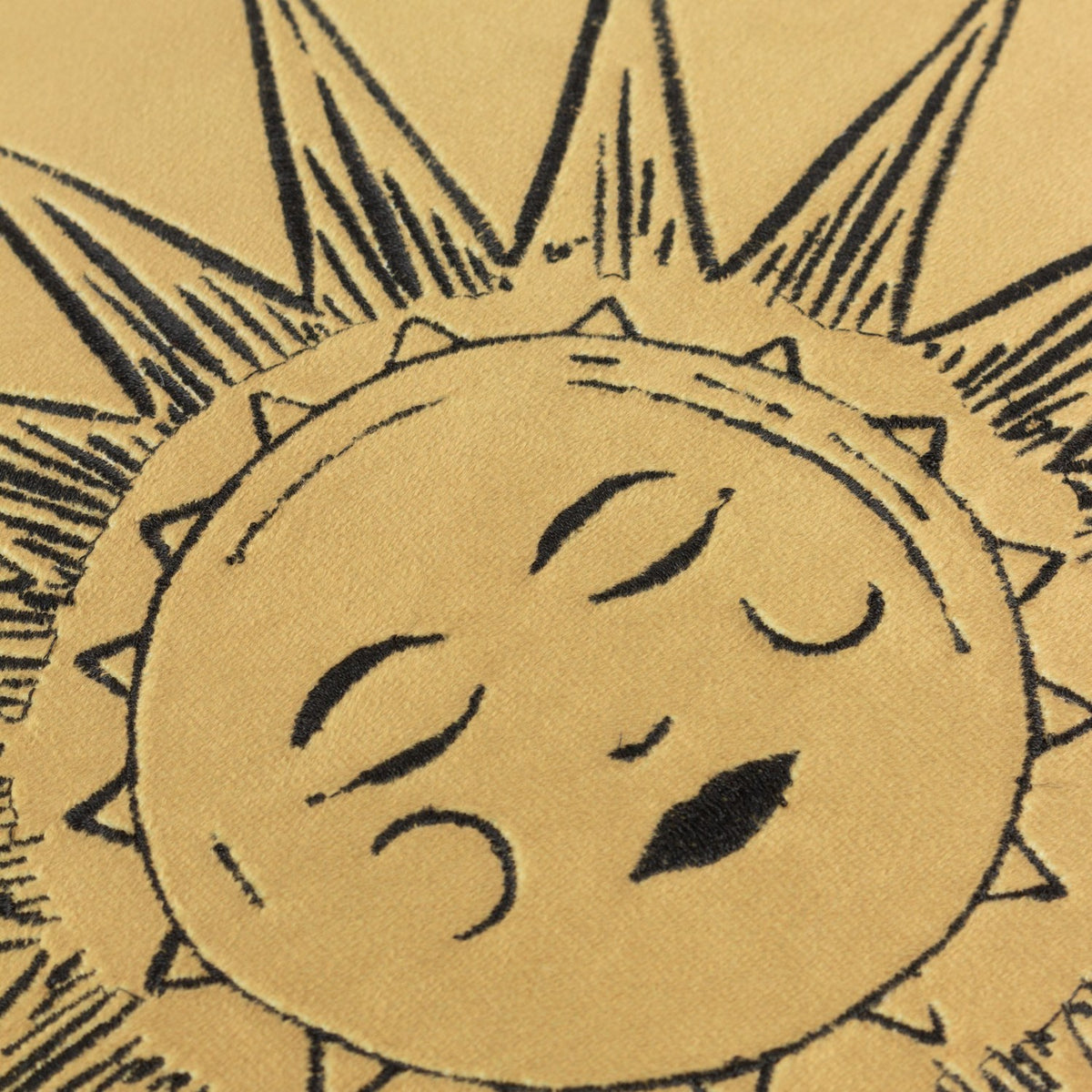Close-up of the Ethereal Abstract Velvet Cushion in Gold Dust, showing an embroidered sun face with closed eyes on gold velvet fabric with a sunburst border.