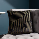 Evoke Geometric Velvet Cushion in black, featuring a gold metallic angular pattern on velvet fabric, styled on a grey sofa in a living room setting.