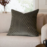 Evoke Geometric Velvet Cushion in charcoal with gold-toned hexagonal pattern, shown on a beige sofa in a living room setting.