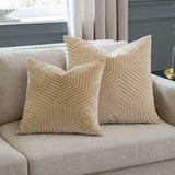 Two Evoke Geometric Velvet Cushions in ivory, cut-velvet hexagonal pattern with a golden sheen, styled on a beige sofa in a living room setting.
