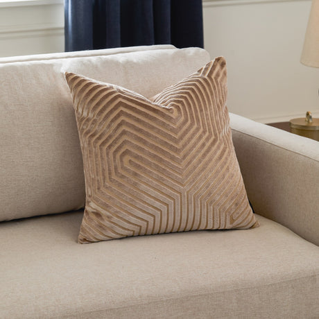 Evoke Geometric Velvet Cushion in beige with cut-velvet chevron pattern and fine gold thread detailing, shown on a light upholstered sofa.