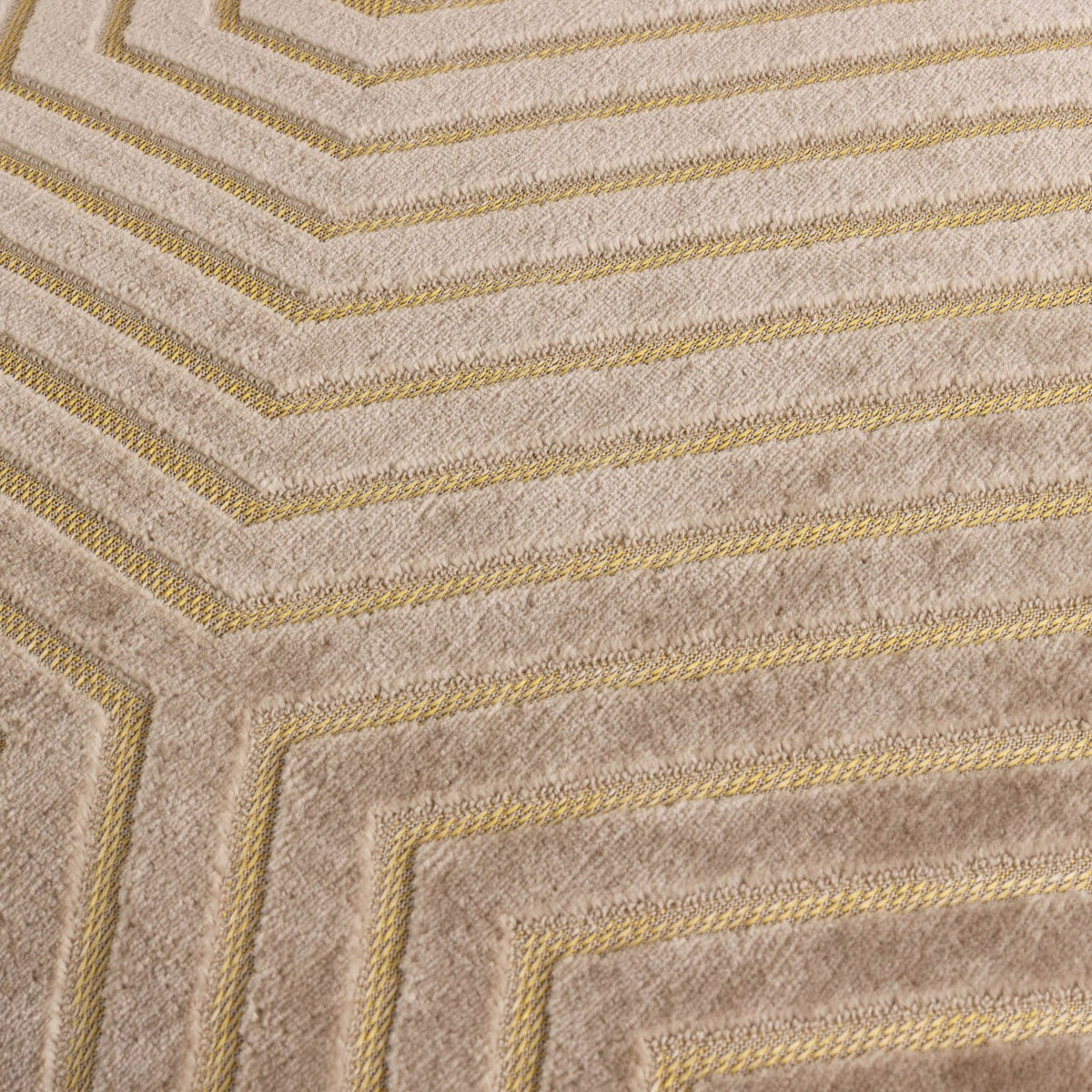 Close-up of the Evoke Geometric Velvet Cushion in beige, showing cut-velvet chevron lines with fine gold threads tracing the channels between the raised pile.