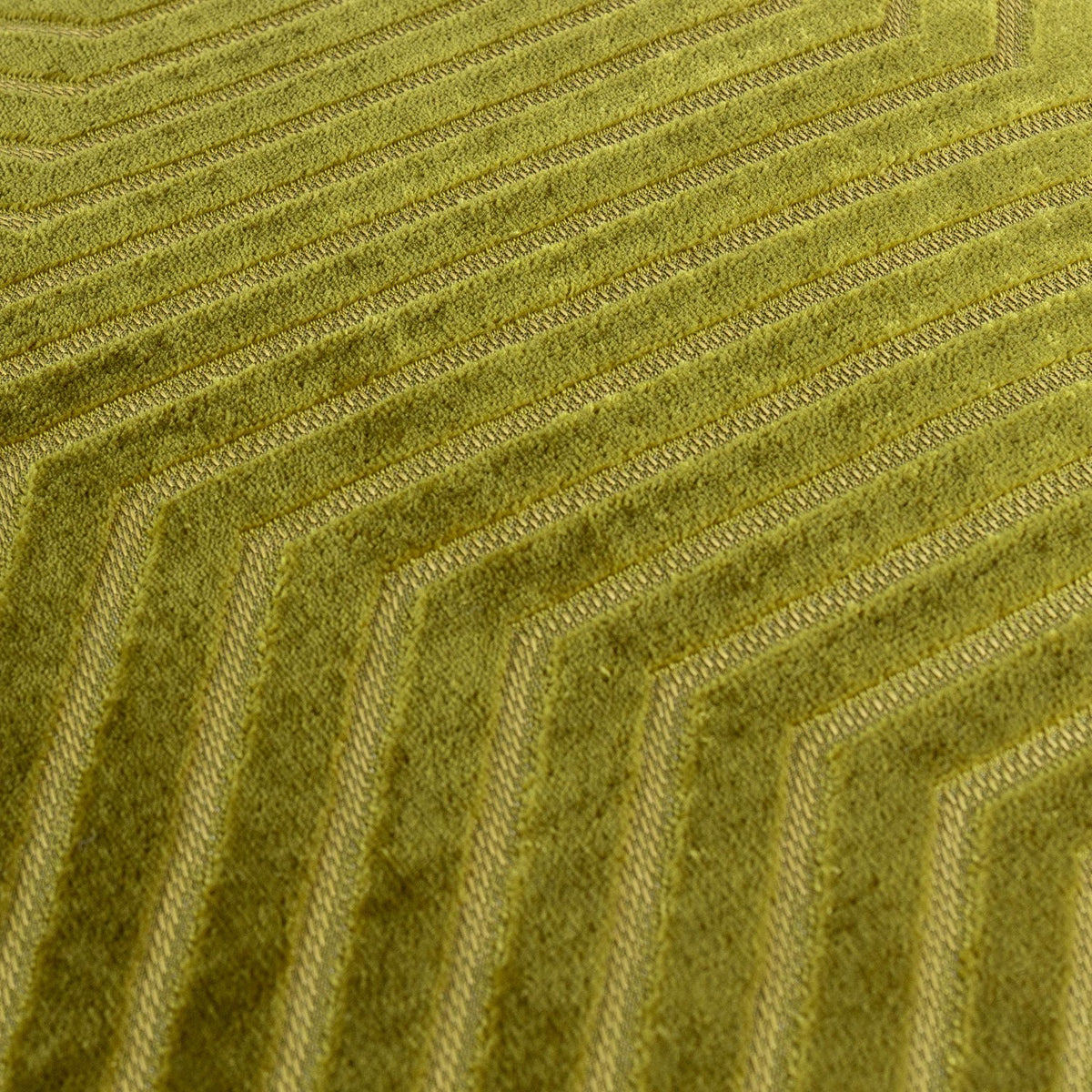Close-up of the Evoke geometric velvet cushion in olive and chartreuse, showing interlocking chevron lines textured into the cut pile fabric.