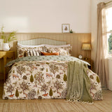 Fable Reversible Animal Duvet Cover Set in Willow Green on a bed, showing the cream woodland-print side with deer, foxes and hares, paired with striped cushions and a green throw.