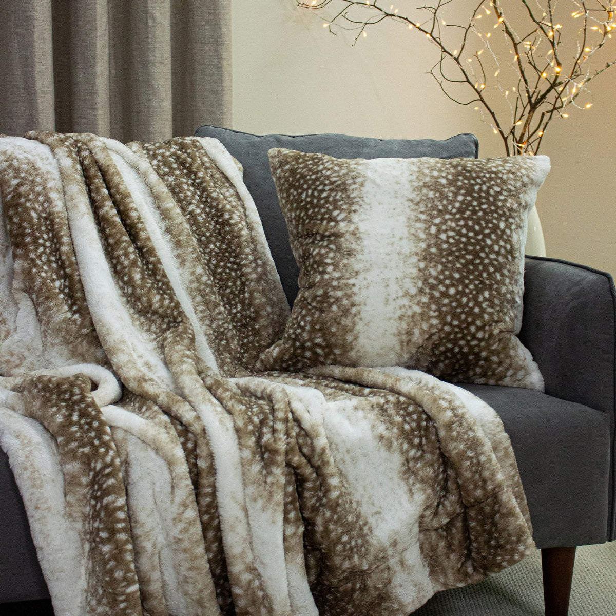 Fawn Animal Faux Fur Throw in brown and cream draped over a grey armchair with a matching cushion, faux fur pile with dappled deerskin-style print.