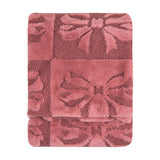 Folded faux fur throw in dusky pink with a raised bow pattern, blending shaggy and boucle textures, shown on a plain white background.