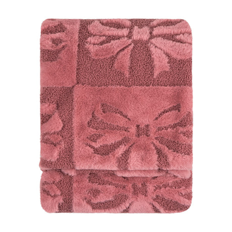 Folded faux fur throw in dusky pink with a raised bow pattern, blending shaggy and boucle textures, shown on a plain white background.