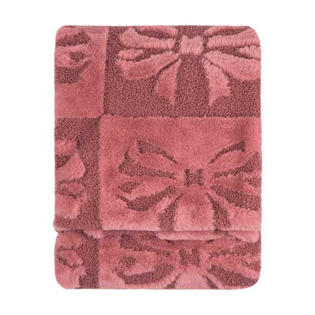 Folded faux fur throw in dusky pink with a raised bow pattern, blending shaggy and boucle textures, shown on a plain white background.