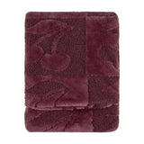 Folded faux fur throw in Morello purple with a checkerboard of smooth pile and boucle squares featuring a raised cherry design, shown on a plain white background.